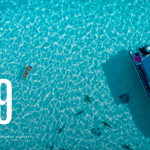 Aerial over turquoise water with boat and woman swimming from National Geographic Best Trips 2019